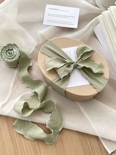 an open gift box with a green ribbon tied around it on top of a table