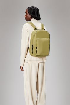 a woman wearing a green backpack and white pants