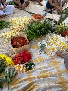 several people sitting on the ground with baskets full of flowers in front of them,