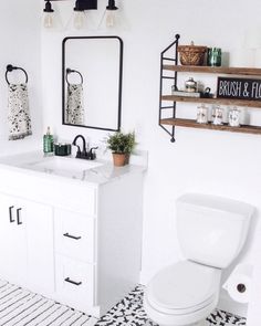 a white toilet sitting next to a sink in a bathroom under a mirror and shelves