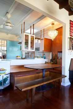 a kitchen with wood floors and white walls, including a wooden dining table surrounded by benches