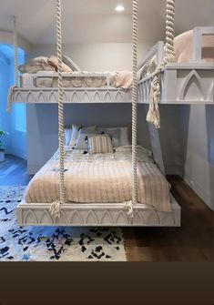 a bunk bed with two sets of swings on the top and bottom, in front of a blue wall