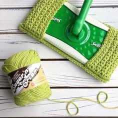 a green mop sitting next to a ball of yarn