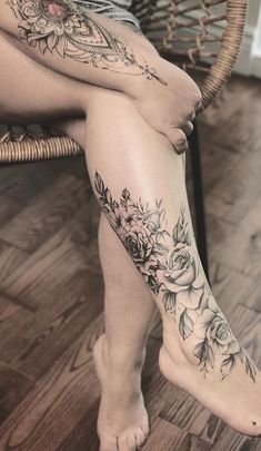 a woman sitting on top of a chair next to a wooden floor with tattoos on her legs