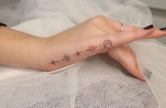 a woman's hand with a small star and moon tattoo on it