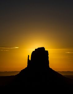 the sun is setting behind a rock formation