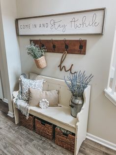 a bench with baskets and flowers on it in front of a sign that says come in and stay fishie