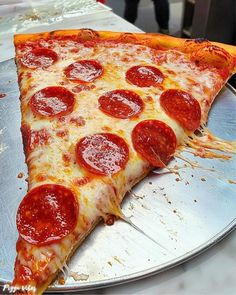 a large slice of pepperoni pizza on a pan