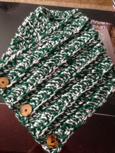 a green and white knitted scarf with buttons