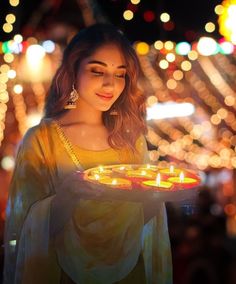 a woman holding a plate with lit candles on it