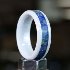 two wedding rings with blue and green marble inlays sitting on top of each other