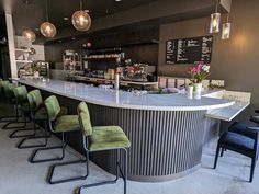 an empty bar with green chairs at the counter