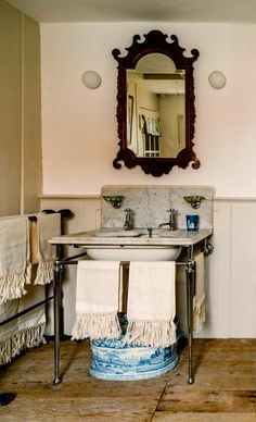 a bathroom sink sitting under a mirror next to a towel rack with two towels on it