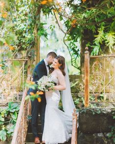 a bride and groom are kissing on the steps in front of an orange - colored arbor