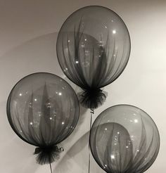 three clear balloons are hanging on the wall in front of a white wall with black accents