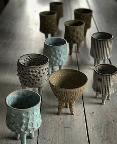 several ceramic cups sitting on top of a wooden table next to each other in different shapes and sizes