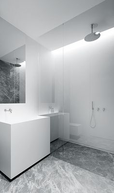 a modern bathroom with marble flooring and white walls, along with a large mirror on the wall