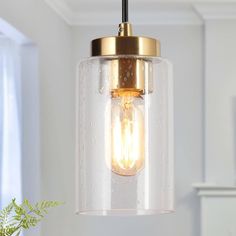 a clear glass light fixture hanging from a ceiling in a room with white walls and windows