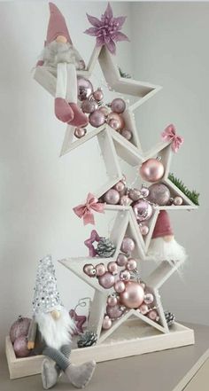 an ornament christmas tree with pink ornaments and santa clause hat on the top