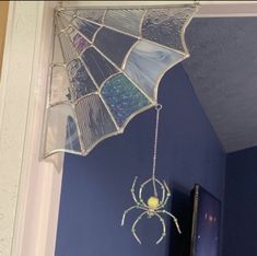 a spider web hanging from the ceiling in a room with blue walls and white trim