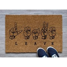 a door mat with the words leave written on it and two hands making peace signs