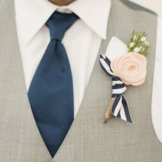 a man wearing a suit and tie with a boutonniere on his lapel