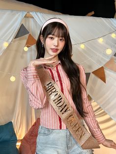 a young woman is posing for the camera with her sash around her neck and headband