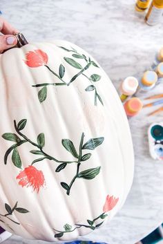 a person holding a painted pumpkin with flowers on it