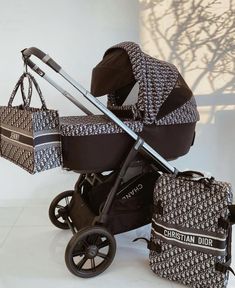 a baby stroller with two diaper bags on the floor next to it's side