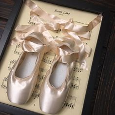 there is a pair of ballet shoes on top of sheet music with ribbon tied around them