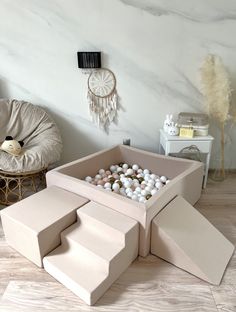 an open cardboard box filled with balls on top of a wooden floor next to a chair