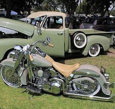 an antique truck and motorcycle are parked in the grass