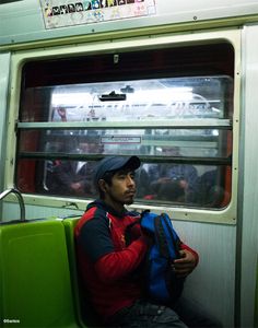 a man sitting on a subway train looking out the window