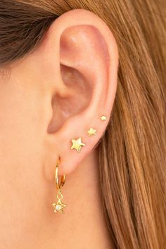 a close up of a person wearing gold stars on their ear and behind the ear