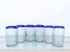 five blue and white glasses lined up on a shelf