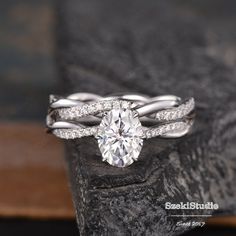 a diamond ring on top of a rock with two bands around the band and an oval cut