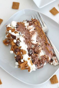 a piece of cake with marshmallows and chocolate chips on the side sitting on a white plate