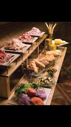 an assortment of food is displayed on a table with breads and salads in bowls