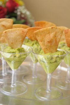 small glasses filled with guacamole and tortilla chips