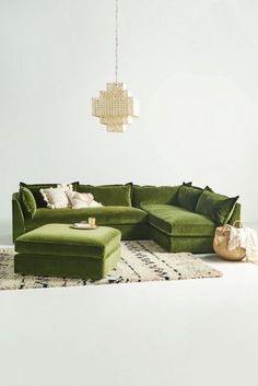 a green sectional couch sitting on top of a rug in front of a white wall