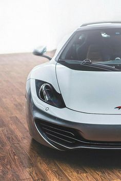 a white sports car parked on top of a wooden floor