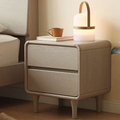 a night stand with a cup on it next to a bed