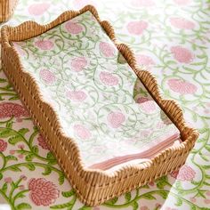 a wicker basket sitting on top of a table covered in pink and green flowers