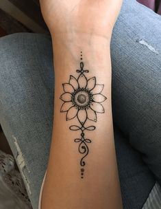 a woman's arm with a black and white tattoo design on the left wrist