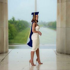 a woman in a graduation cap and gown is walking through an archway with her hand on her hip