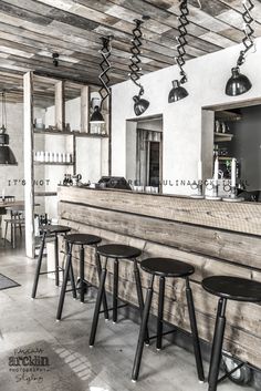 the bar has four stools in front of it and several lights hanging from the ceiling