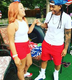 two people standing next to each other in red shorts