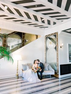 a man and woman sitting on a couch in a hotel room with black and white striped walls