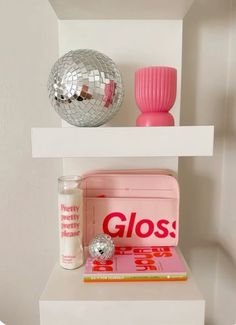 a white shelf with some pink items on it and a disco ball in the corner