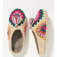 a pair of crocheted slippers with tassels on the top and bottom